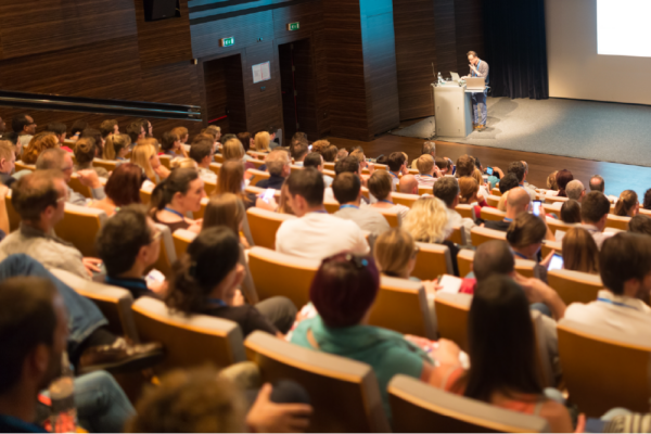 Dynamic conference with diverse audience engaging with speaker and technology in modern auditorium.