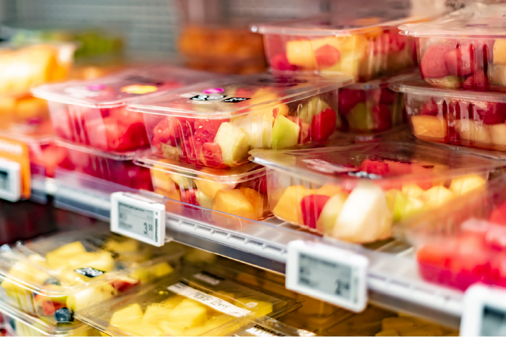 Colorful, fresh fruit cups displayed in a grocery store, perfect for healthy snacking.